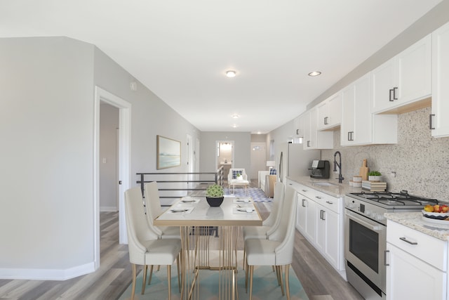 kitchen with white cabinetry, light stone countertops, wood-type flooring, and high end stove