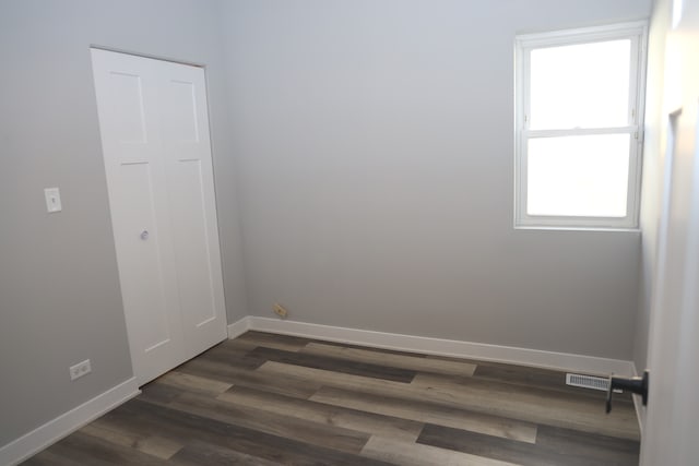 empty room with a healthy amount of sunlight and dark hardwood / wood-style flooring