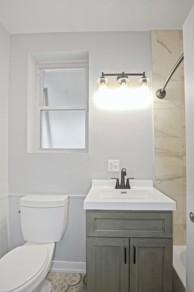 full bathroom featuring tiled shower / bath, vanity, and toilet