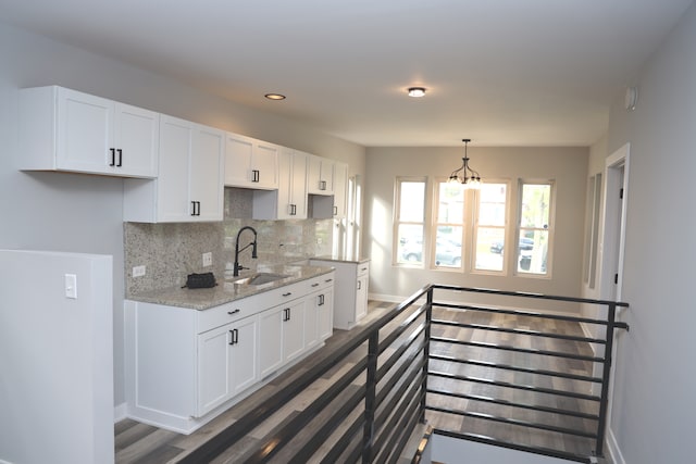 kitchen with light stone countertops, sink, and white cabinets