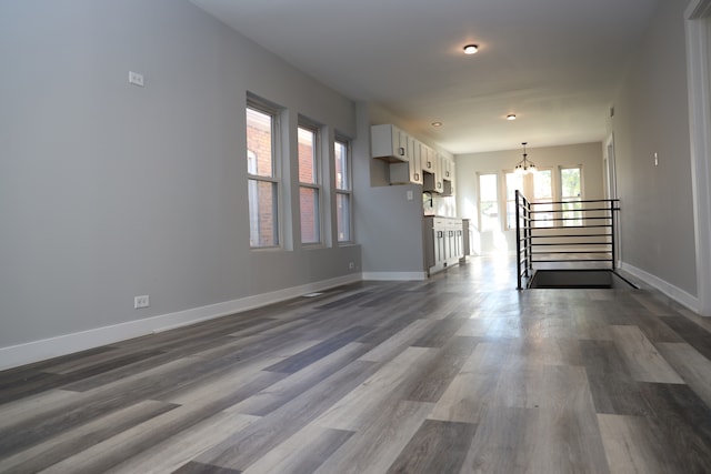 unfurnished living room with a notable chandelier and dark hardwood / wood-style floors