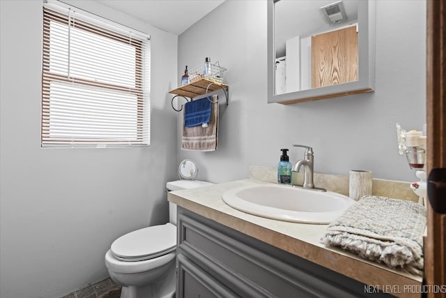 bathroom with vanity, toilet, and a healthy amount of sunlight