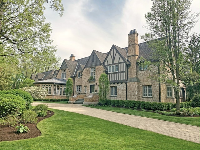 tudor-style house featuring a front lawn