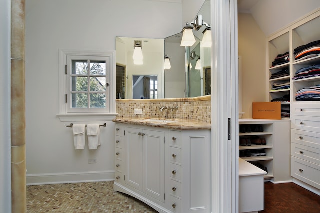 bathroom with vaulted ceiling, vanity, and tasteful backsplash