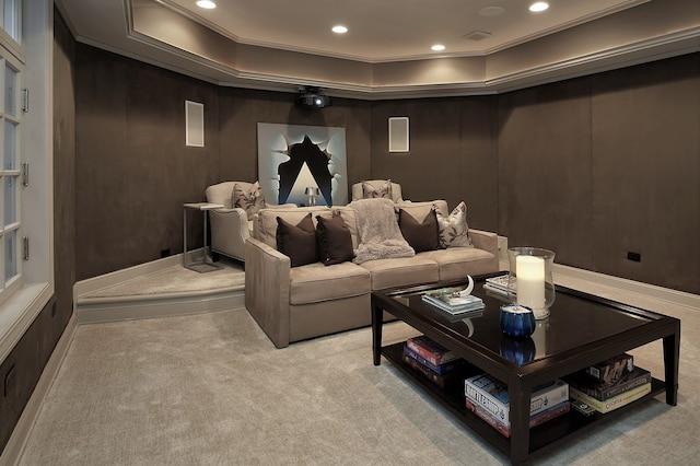 cinema with a raised ceiling, ornamental molding, and light carpet