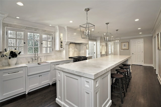 kitchen featuring white cabinets, decorative light fixtures, dark wood-type flooring, a center island, and a notable chandelier