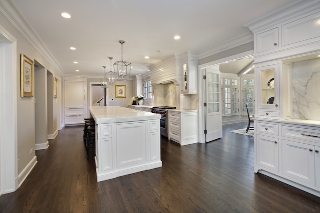 kitchen featuring high end range, white cabinetry, hanging light fixtures, and a kitchen island