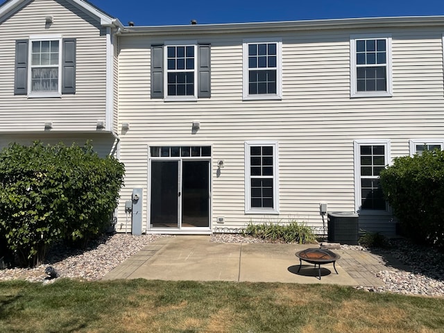 back of house with central AC unit, a yard, a patio, and an outdoor fire pit