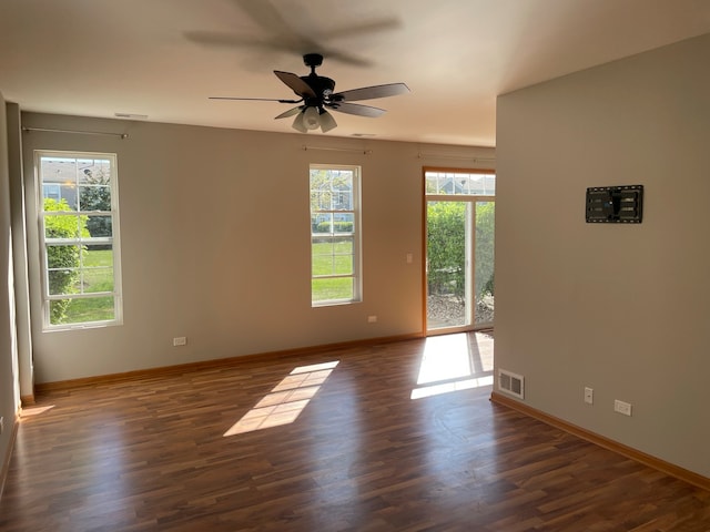 empty room with ceiling fan, plenty of natural light, and dark wood-type flooring