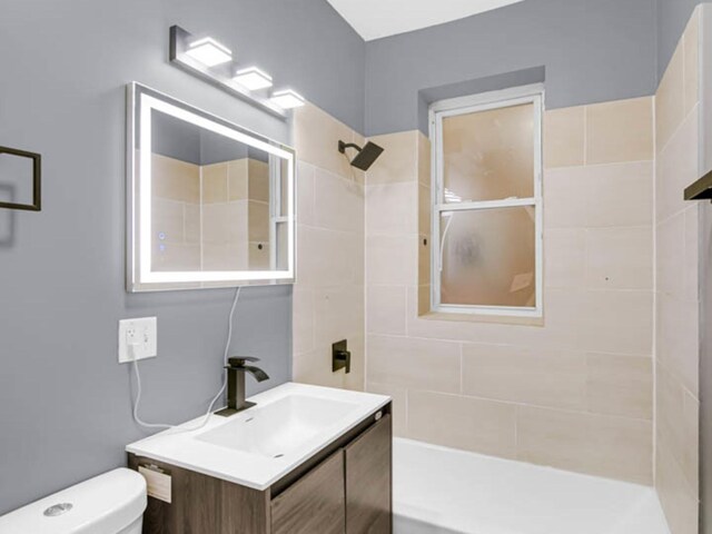 bathroom with vanity, toilet, and a tile shower