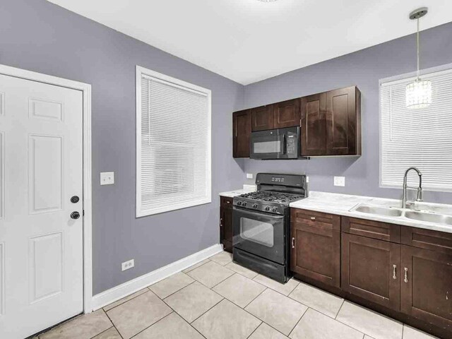 kitchen with light tile patterned floors, black appliances, sink, hanging light fixtures, and dark brown cabinetry