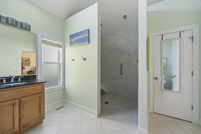 bathroom featuring tile patterned floors, toilet, vanity, and tiled shower