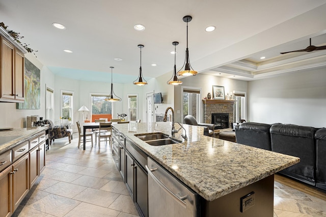 kitchen with dishwasher, sink, hanging light fixtures, an island with sink, and a tray ceiling