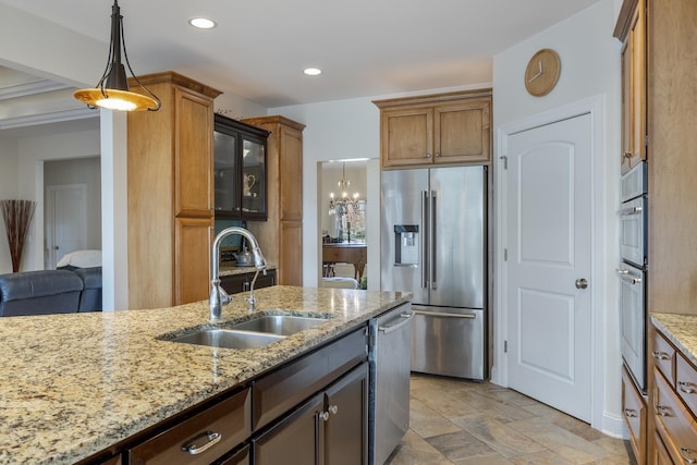 kitchen with decorative light fixtures, light stone counters, sink, and appliances with stainless steel finishes