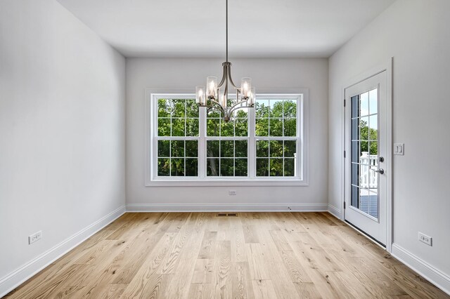 unfurnished dining area featuring light hardwood / wood-style flooring and a chandelier