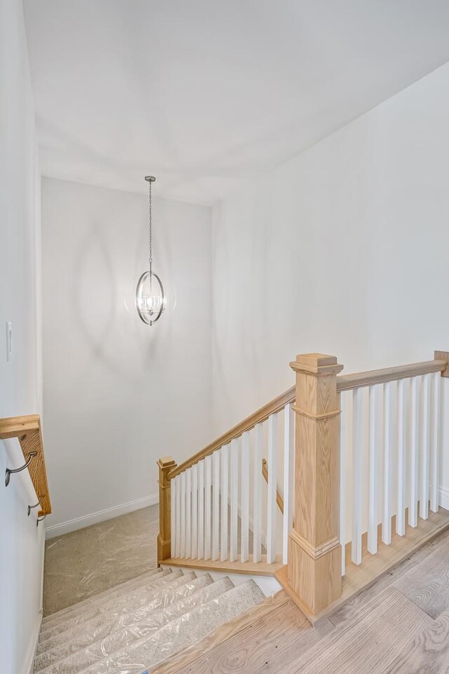 stairway featuring hardwood / wood-style flooring and a notable chandelier