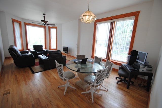 dining area featuring a wealth of natural light, ceiling fan with notable chandelier, and wood-type flooring