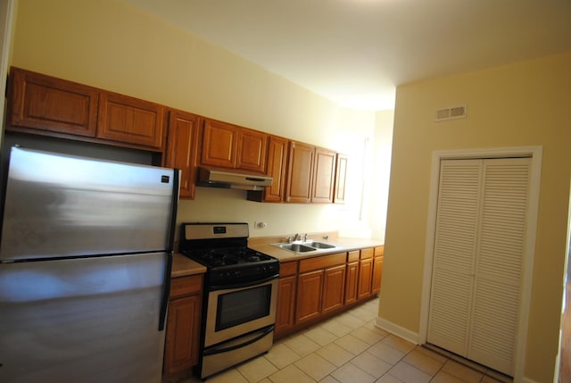 2701 W Congress Pkwy, Chicago, IL 60612 - kitchen featuring appliances with stainless steel finishes, under cabinet range hood, light tile patterned floors, brown cabinets, and light countertops