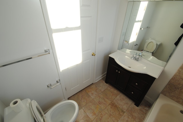 bathroom featuring vanity, toilet, and a washtub