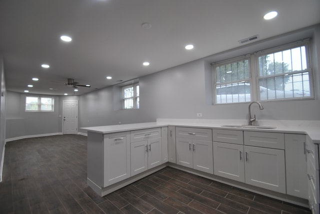 kitchen with plenty of natural light, kitchen peninsula, sink, and dark hardwood / wood-style flooring