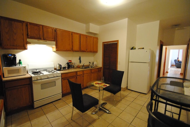 2701 W Congress Pkwy, Chicago, IL 60612 - kitchen with white appliances, under cabinet range hood, light countertops, brown cabinets, and light tile patterned floors