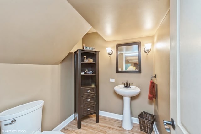 bathroom with toilet, hardwood / wood-style floors, and vaulted ceiling