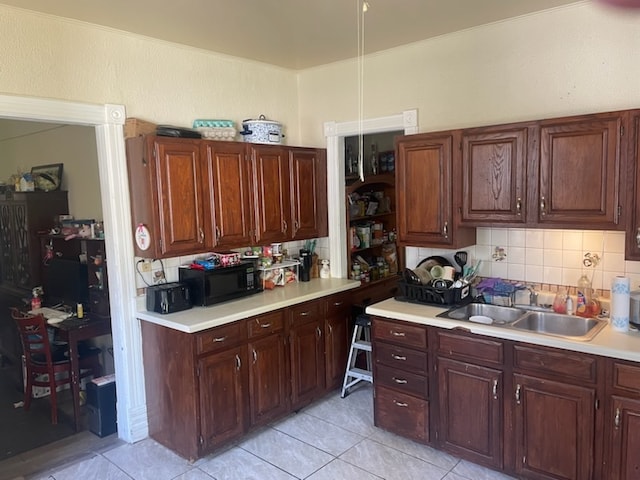 kitchen featuring backsplash, light tile patterned floors, and sink