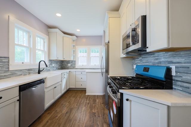 kitchen featuring stainless steel appliances, white cabinetry, dark hardwood / wood-style floors, and backsplash