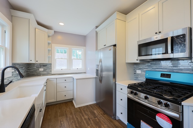 kitchen featuring appliances with stainless steel finishes, decorative backsplash, white cabinetry, dark wood-type flooring, and sink