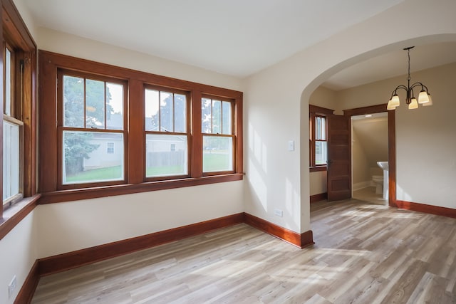 empty room with an inviting chandelier and light hardwood / wood-style floors