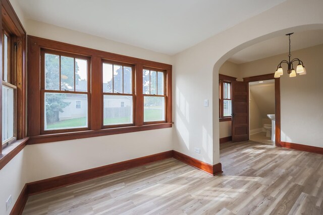 unfurnished dining area with light wood-type flooring and a chandelier