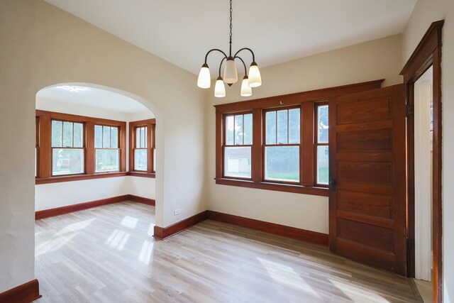 empty room featuring washing machine and dryer, an inviting chandelier, and light hardwood / wood-style flooring