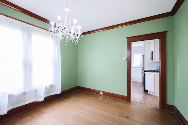 unfurnished room featuring wood-type flooring, ornamental molding, and an inviting chandelier