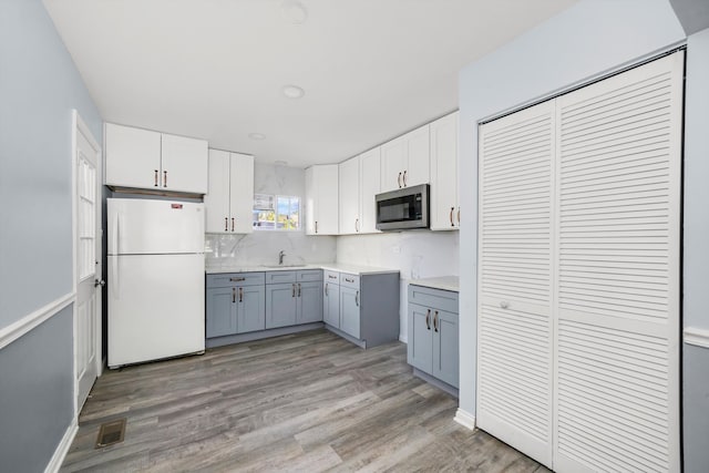 kitchen featuring white cabinets, sink, light hardwood / wood-style floors, and white fridge