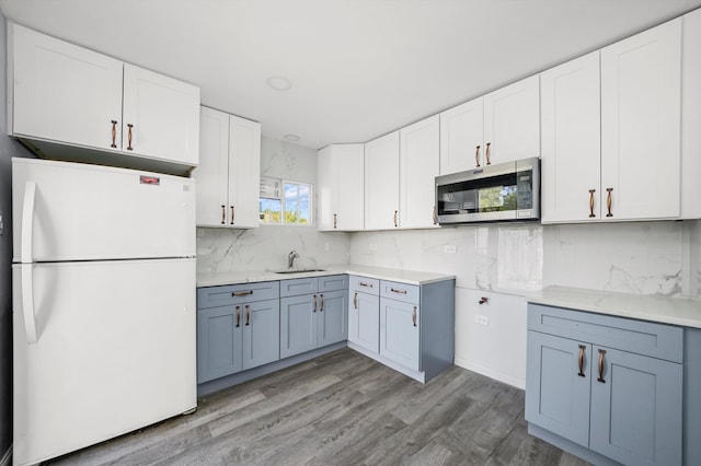 kitchen with light hardwood / wood-style flooring, white cabinetry, and white fridge