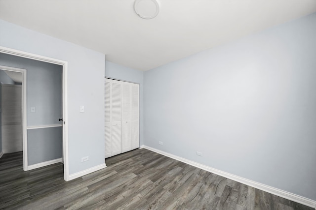 unfurnished bedroom with dark hardwood / wood-style flooring and a closet