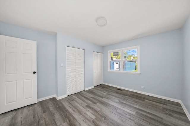 unfurnished bedroom featuring dark hardwood / wood-style floors and multiple closets