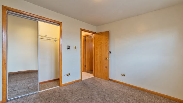 unfurnished bedroom with light carpet and a closet