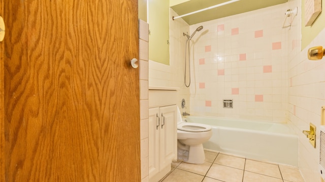 bathroom featuring tiled shower / bath, toilet, and tile patterned flooring