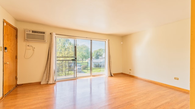 unfurnished room featuring an AC wall unit and light hardwood / wood-style floors