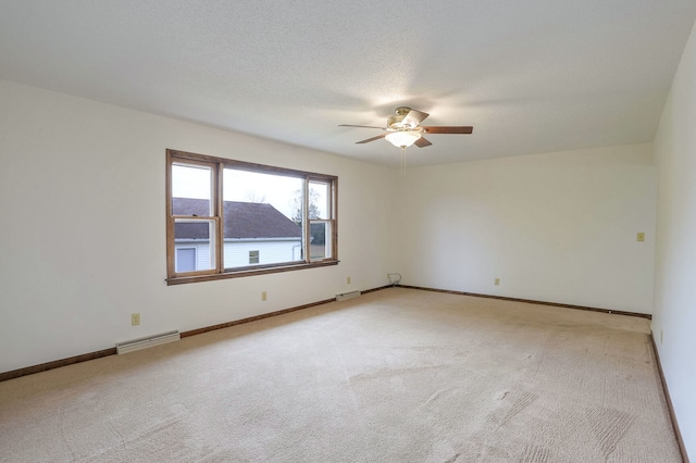 empty room featuring ceiling fan, light carpet, and a textured ceiling