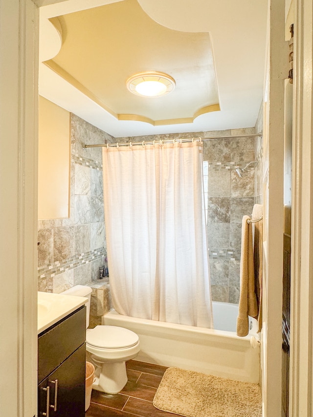 full bathroom featuring toilet, vanity, shower / bath combo, a tray ceiling, and hardwood / wood-style flooring