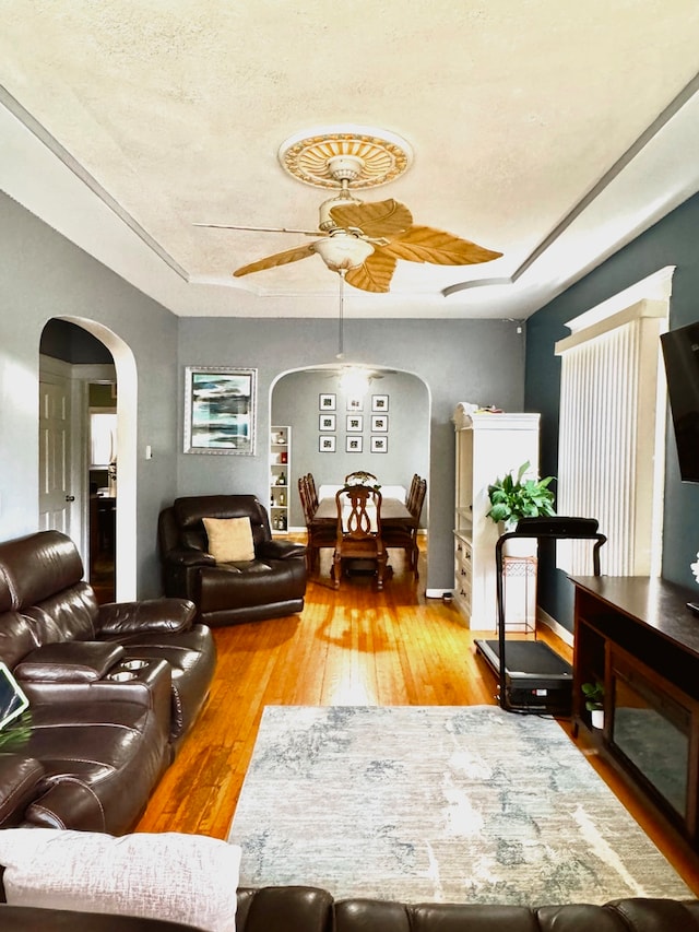 living room featuring a textured ceiling, wood-type flooring, and ceiling fan