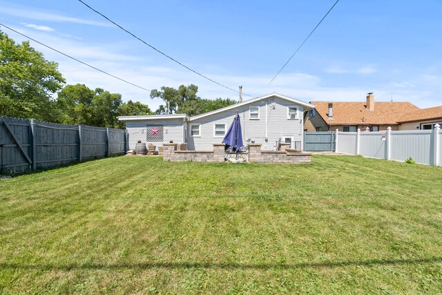 back of property with a fenced backyard and a yard