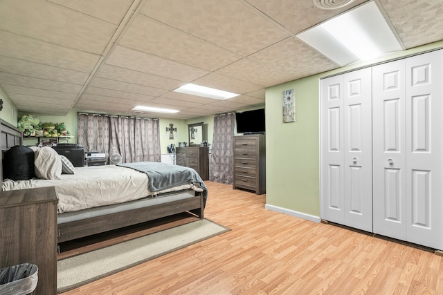 bedroom featuring a drop ceiling, light hardwood / wood-style flooring, and a closet