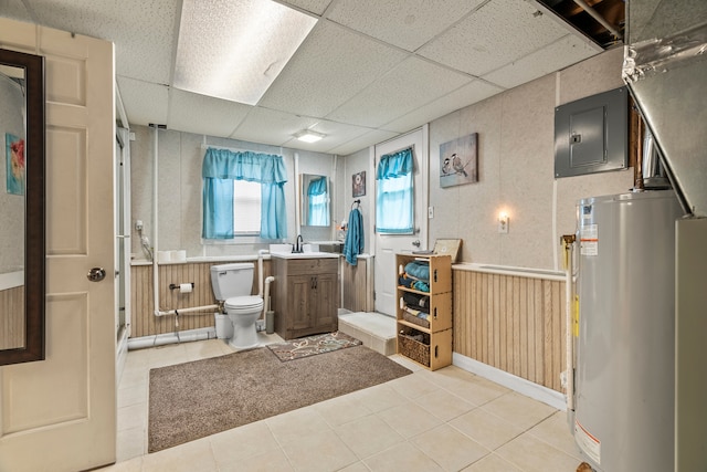 bathroom featuring tile patterned flooring, toilet, electric panel, a drop ceiling, and water heater