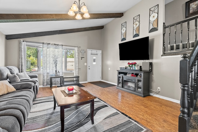 living area with lofted ceiling with beams, stairs, a fireplace, and wood finished floors