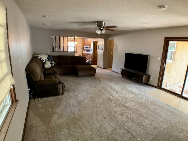 carpeted living room with a textured ceiling and ceiling fan