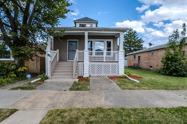 view of front of home with covered porch, a front yard, and fence