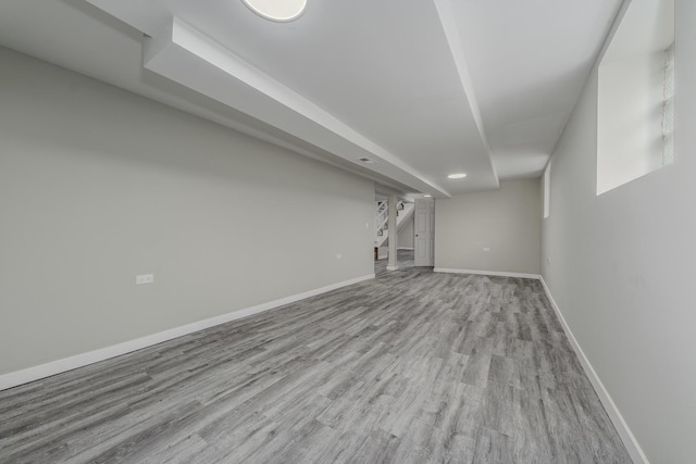 finished basement featuring stairway, wood finished floors, and baseboards